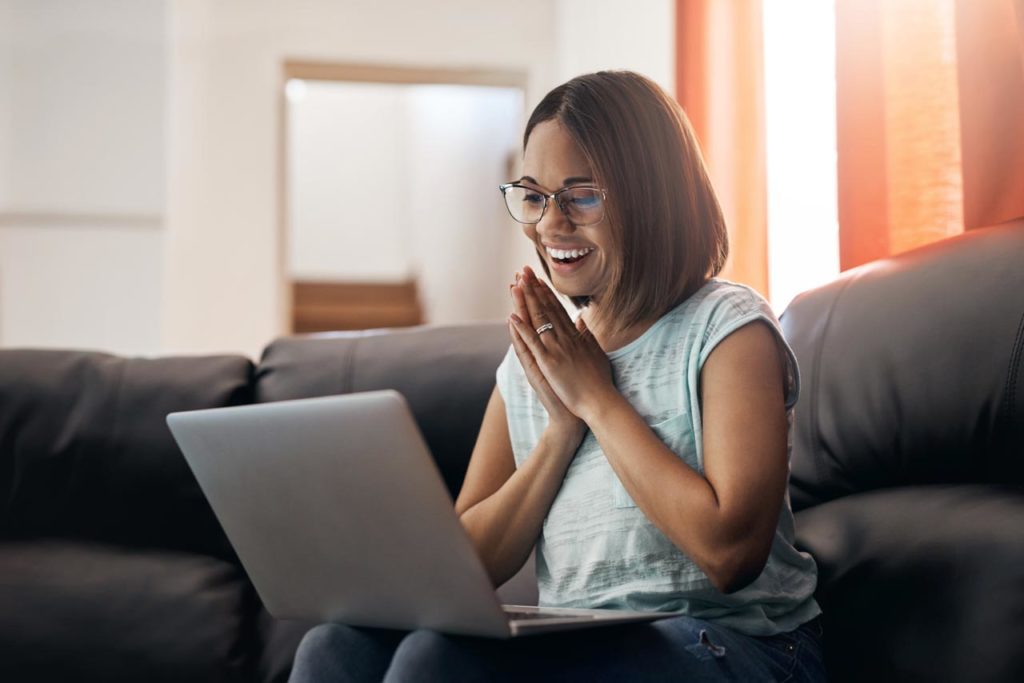 Woman on couch smiling at her laptop
