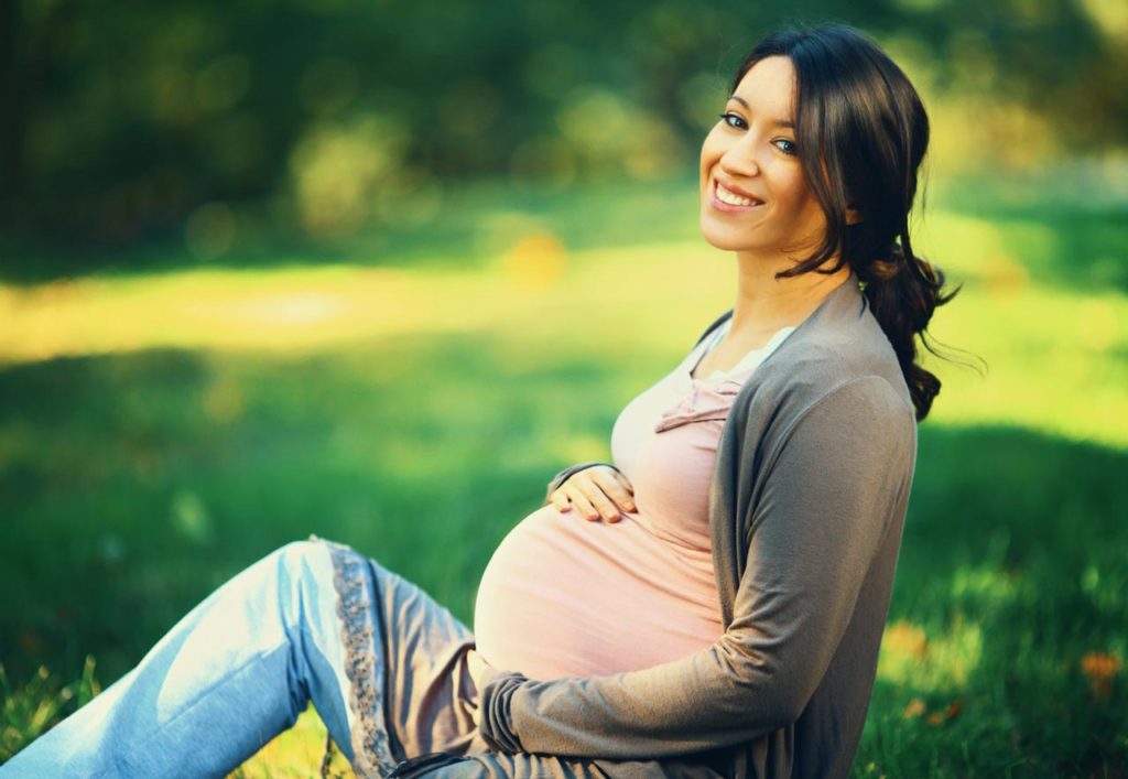 Pregnant woman sitting in grass